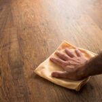 Person's hand in frame caring for hardwood floors by wiping it with an orange microfiber cloth at Preferred Flooring near Breese, IL