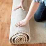 Professional flooring technician rolling out a new carpet to air it out before installing it at Preferred Flooring near Breese, IL