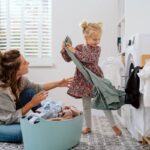 A mother sitting on intricate tile flooring as her daughter pulls laundry out of the dryer at Preferred Flooring near Breese, IL